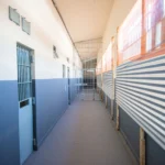 Foto do Presídio de Vespasiano ao entardecer, com muros altos e guarita, simbolizando a segurança.