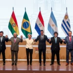 Bandeiras da Polônia e Mercosul, martelo de juiz sobre documentos legais, simbolizando a contestação judicial do acordo.