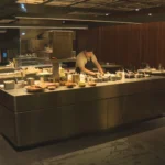 Salão de jantar elegante do restaurante Tuju, com mesas bem arrumadas e iluminação ambiente, refletindo a sofisticação de um restaurante com três estrelas Michelin.