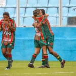 Jogadoras da Copa do Brasil Feminina em campo, com uniforme vermelho e azul, disputando a bola.