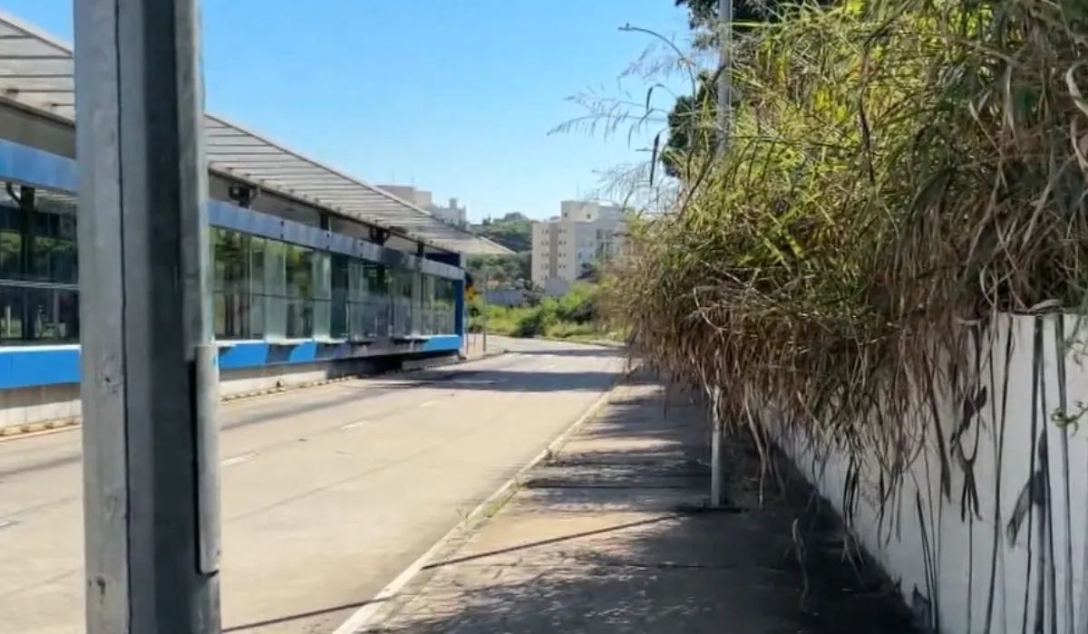 Ônibus BRT de Campinas parado em estação com mato alto e lixo