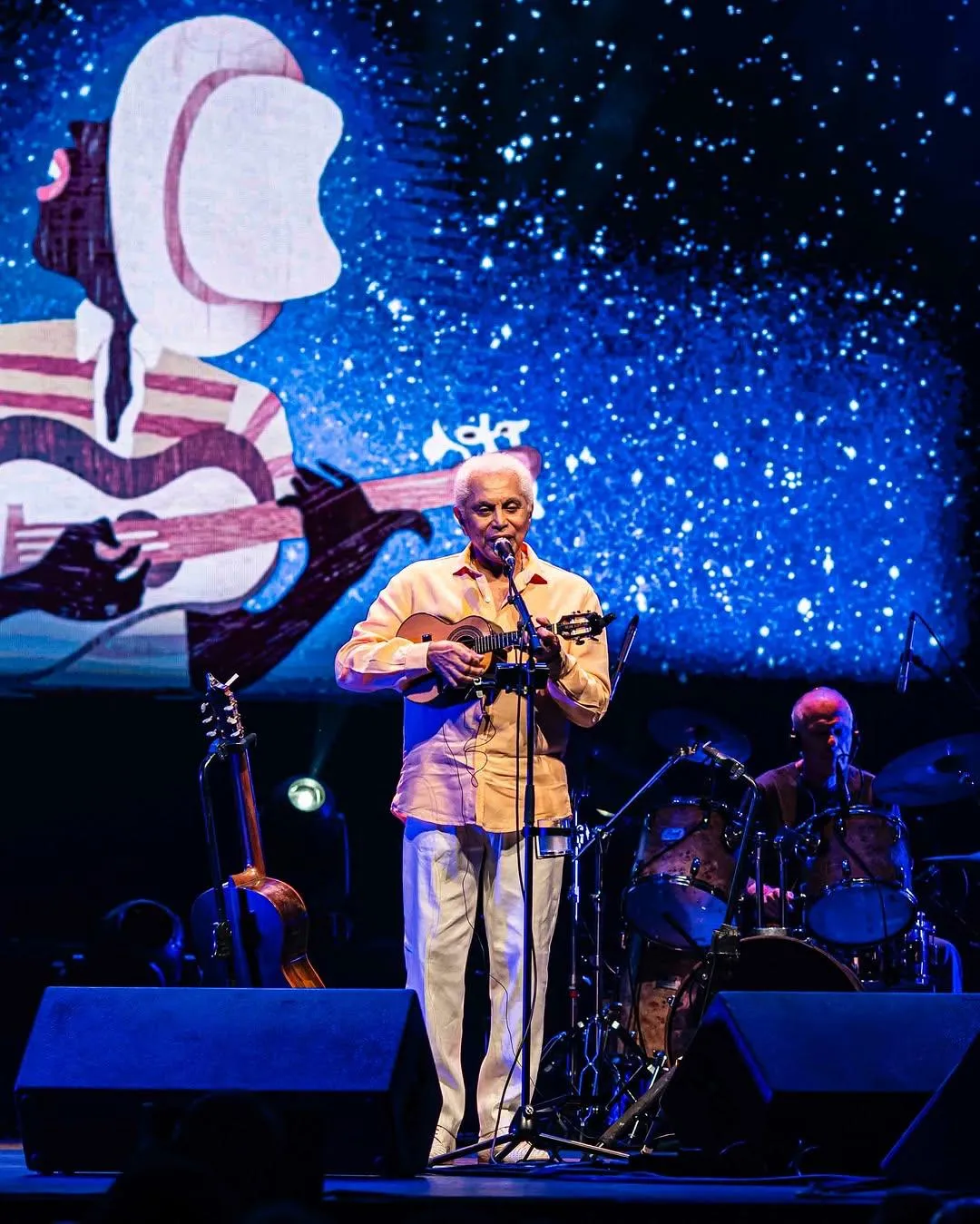Rio de Janeiro à noite com Pão de Açúcar e Cristo Redentor, e pessoas em um evento cultural