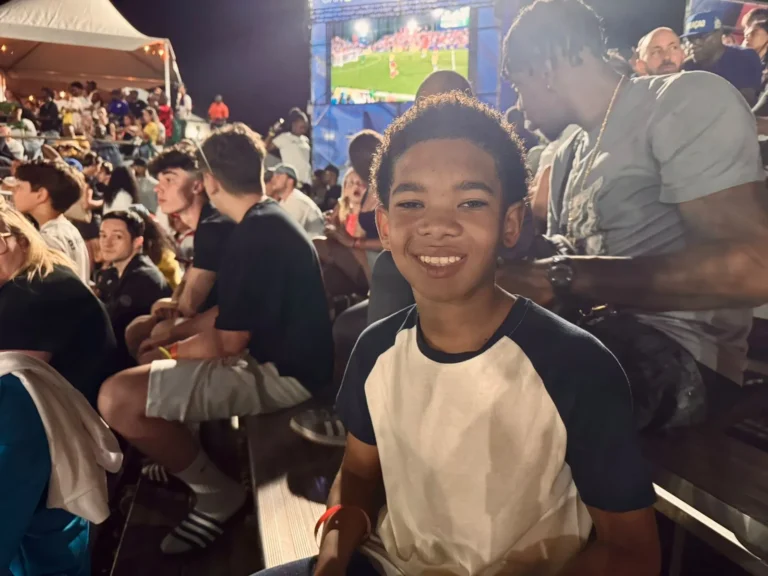 Ronaldinho Gaúcho em campo na Legends Cup em Curaçao, cercado por fãs e comemorações.