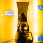 Estádio de futebol com jogo da Série B 2026 em andamento, torcedores assistindo, campo verde