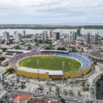 Vista aérea da Arena Batistão em Aracaju, Sergipe, com o campo de futebol e arquibancadas, iluminada pela luz do fim de tarde, antes do jogo Sergipe e Lagarto pela Série D.
