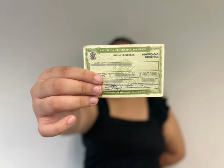 Grupo de jovens eleitores com seus títulos, votando em uma urna eletrônica