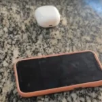 Policial investigando moto com defeito e sacola com drogas e fones, cenário de prisão por tráfico em Piraí.