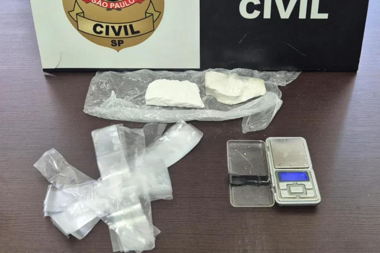 Policiais em ação durante operação contra o tráfico de drogas, com evidências como drogas e um celular explodido sobre uma mesa.