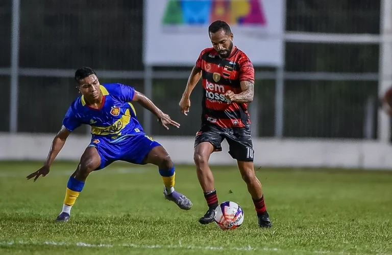 Jogo de futebol entre Trem-AP e Independência-AC pela Copa Norte, com jogadores em ação no gramado iluminado