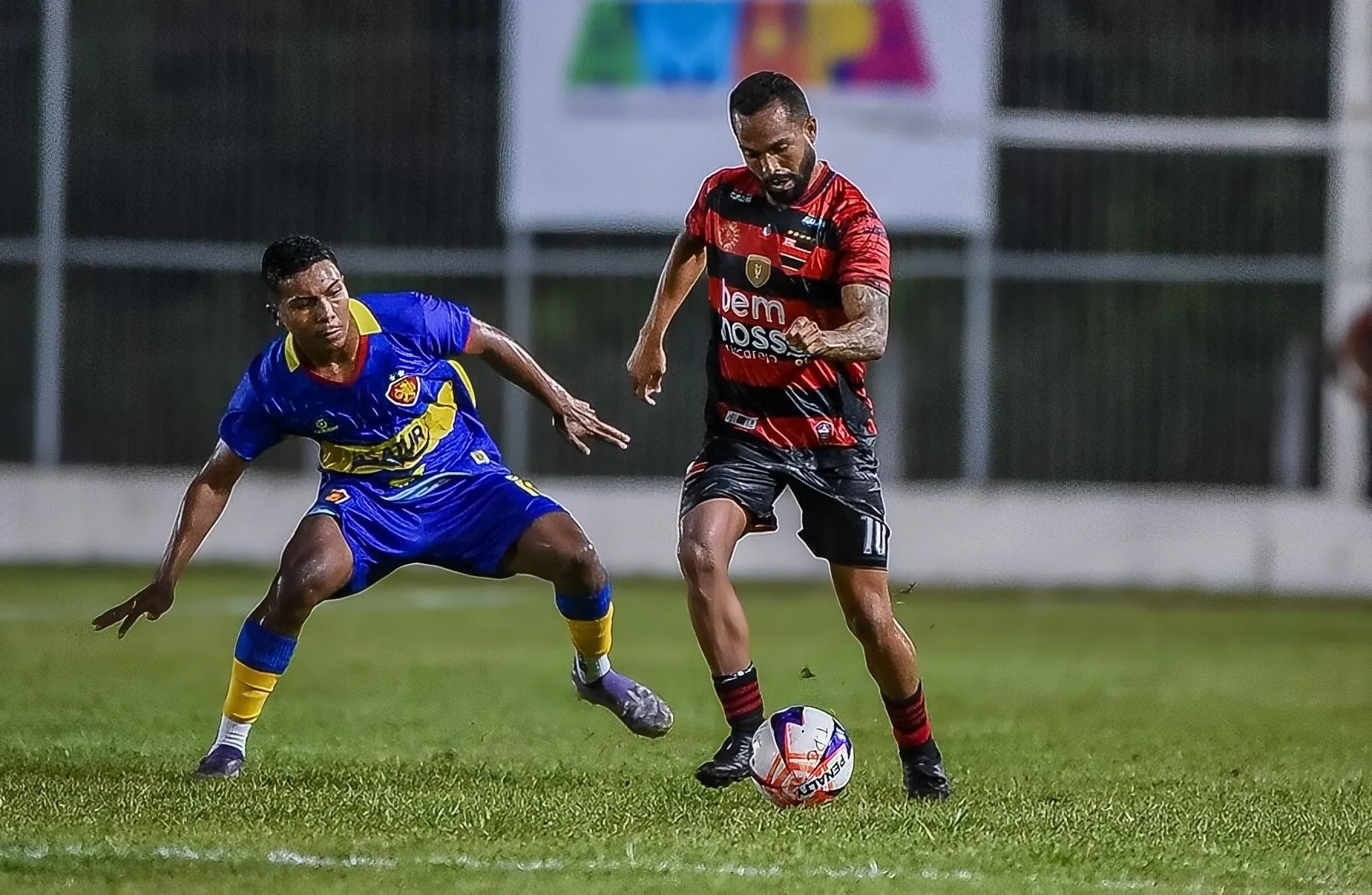 Jogo de futebol entre Trem-AP e Independência-AC pela Copa Norte, com jogadores em ação no gramado iluminado