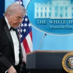 Imagem de Donald Trump discursando, com foco em suas declarações sobre o tiroteio e o conflito no Irã.