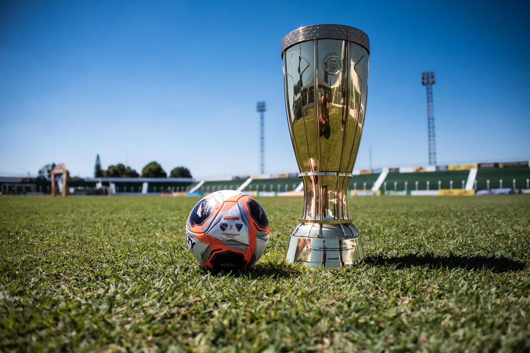 Jogadores em campo durante jogo da Bezinha 2026, com o Estádio Teixeirão ao fundo