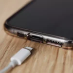 Smartphone conectado à tomada, carregando a bateria, com foco em segurança.