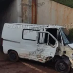 Van branca danificada após acidente em rodovia, atingindo placa e árvore
