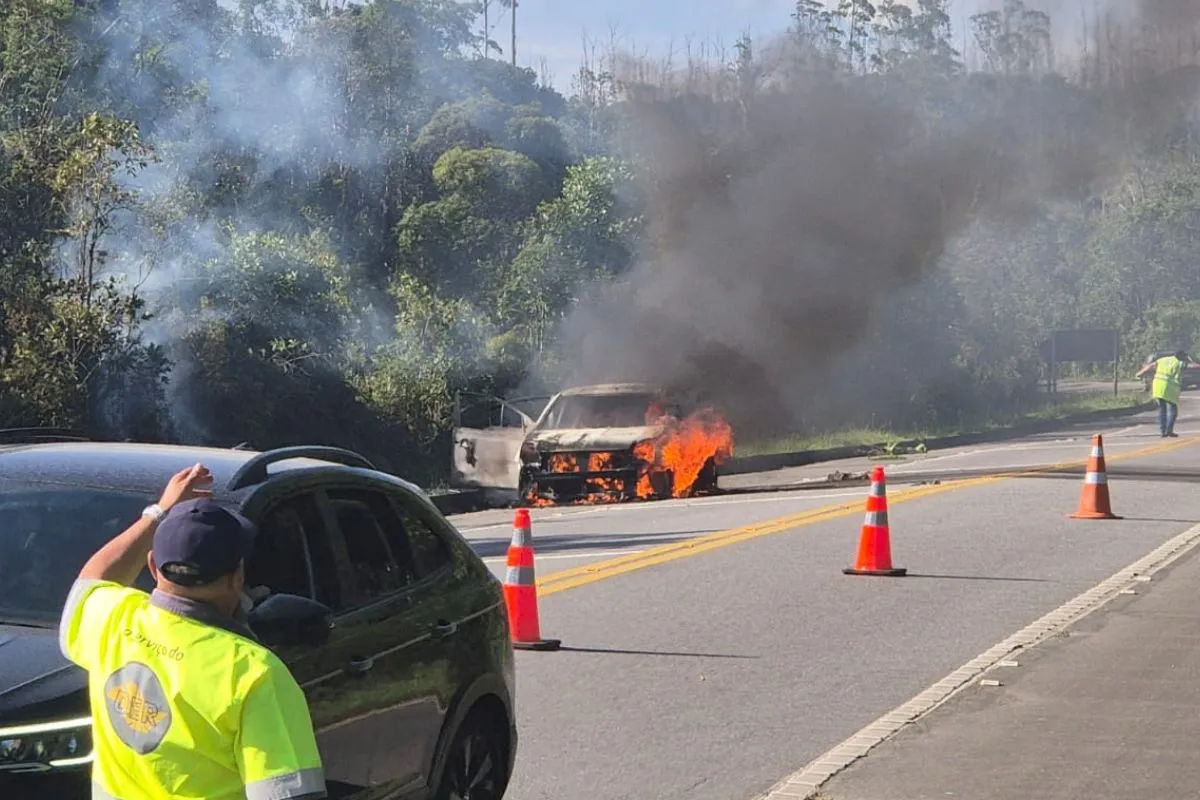 Carro em chamas na Rodovia Oswaldo Cruz, Ubatuba, com trânsito parado e equipes de resgate.