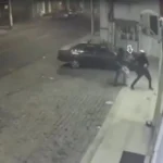 Dois homens mascarados tentando quebrar vitrine de loja com pedras em Campos