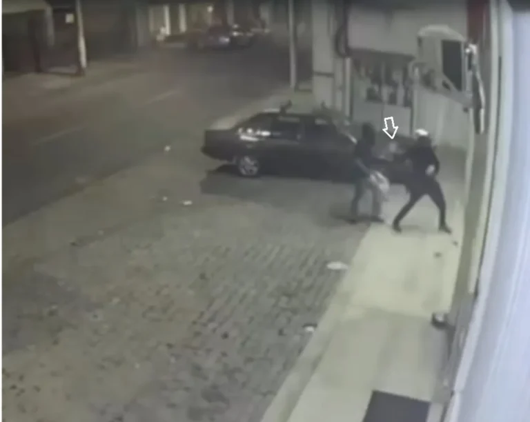 Dois homens mascarados tentando quebrar vitrine de loja com pedras em Campos