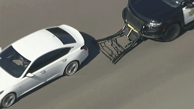 Carro branco destruído após perseguição policial nos EUA e colisão com muro