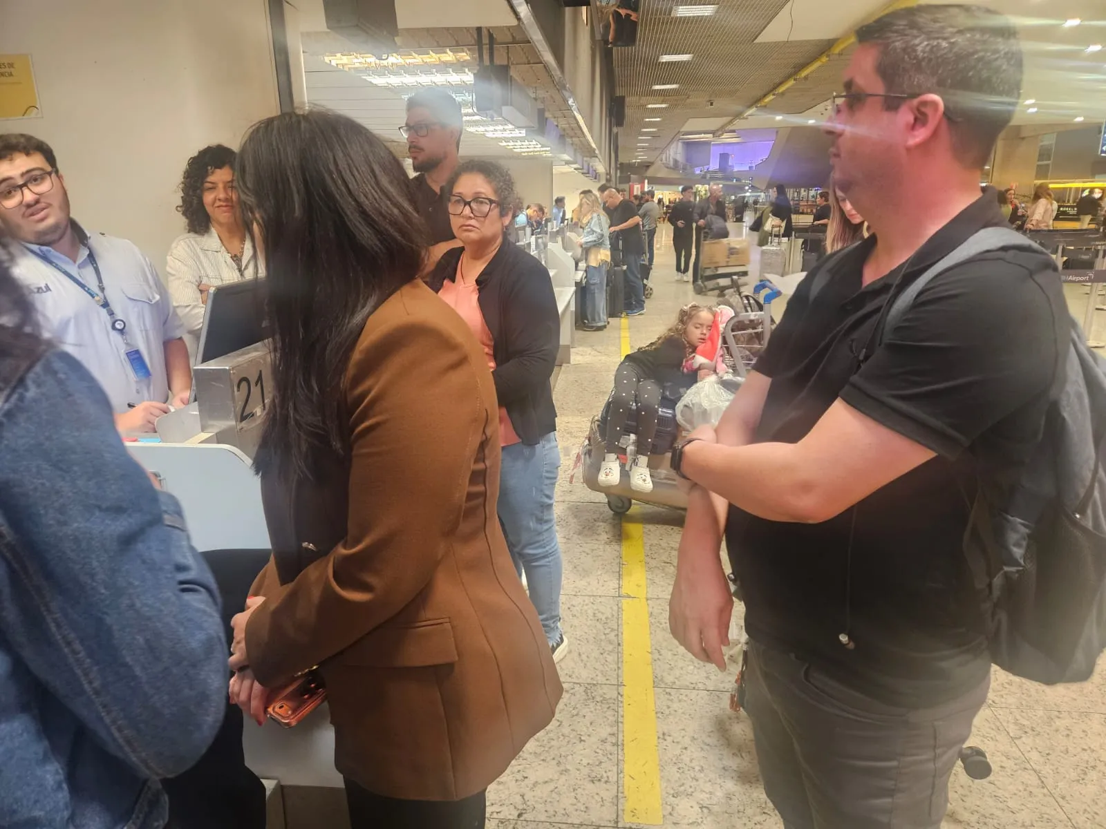 Pessoas aguardando em saguão de aeroporto com voos cancelados Confins
