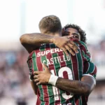 Dois atacantes do Fluminense, John Kennedy e Castillo, comemorando um gol juntos em campo.
