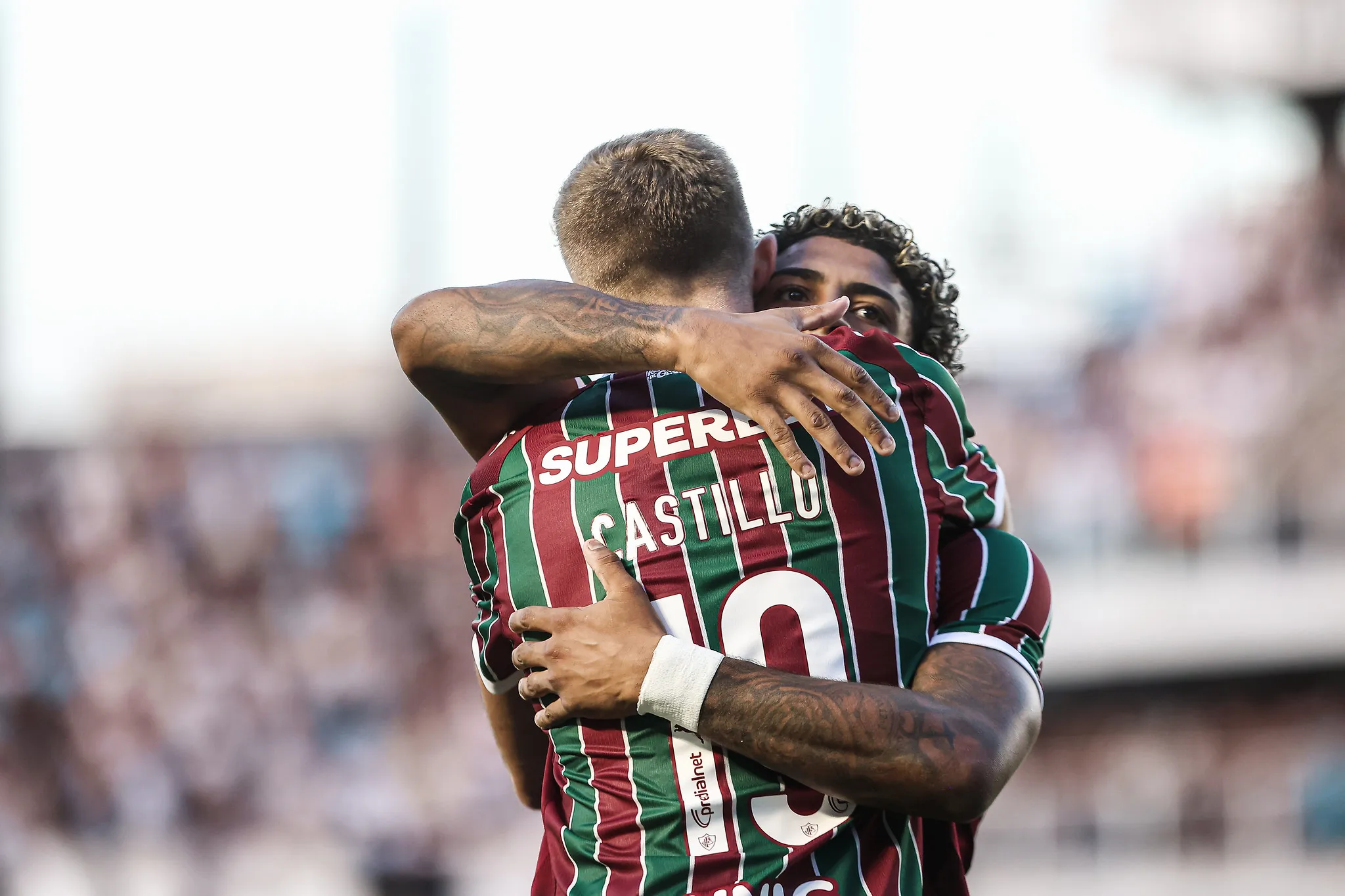 Dois atacantes do Fluminense, John Kennedy e Castillo, comemorando um gol juntos em campo.